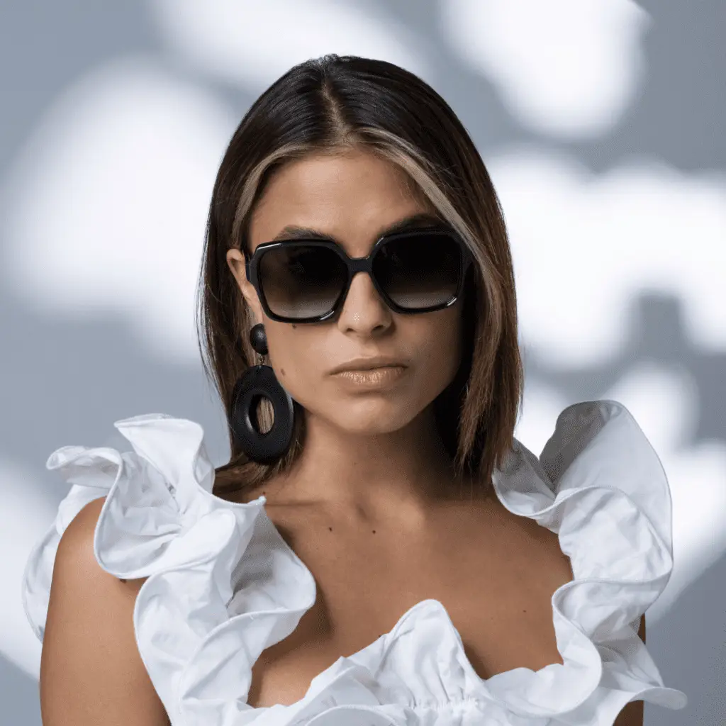 Frau mit Colibris Sonnenbrille und weisser Rüschenbluse.