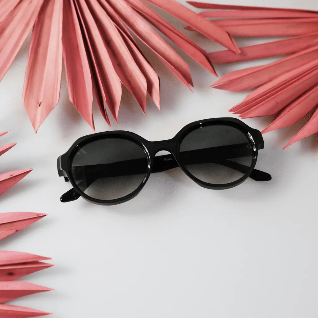 Colibris Sonnenbrille auf weißem Hintergrund mit rosa Blättern.