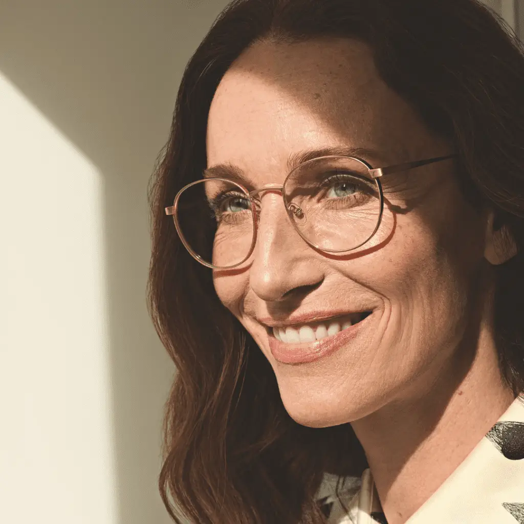 Lächelnde Frau mit Götti Switzerland Brille und Sonnenlicht.