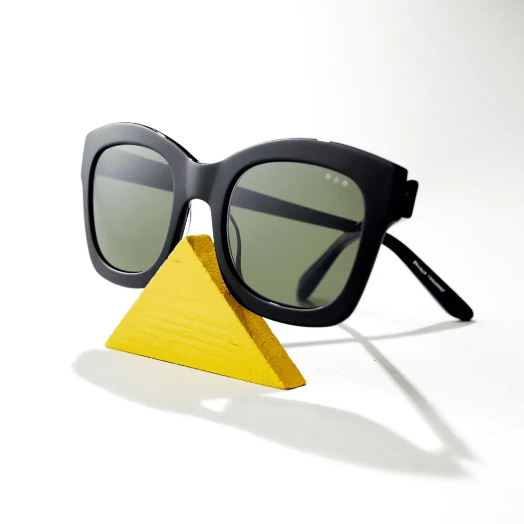 Schwarze Sonnenbrille von Hamburg Eyewear auf gelbem Dreieck.