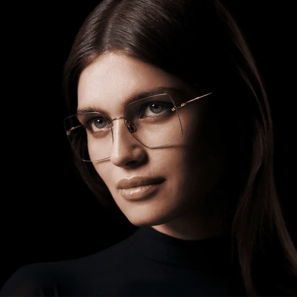 Frau mit Gold-Brille und dunklem Hintergrund.